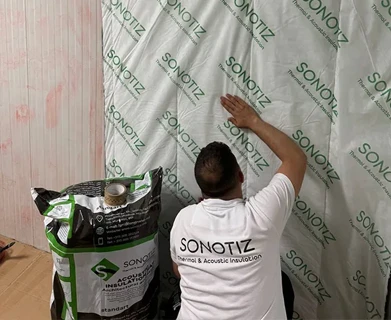 Technician installing SONOTIZ soundproofing and thermal insulation system on wall panel